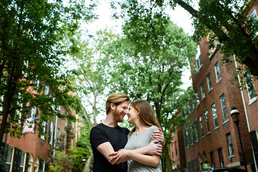 A couple hold each other in the streets of center city during engagement session.